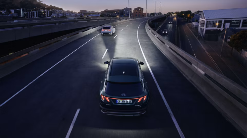 The Hyundai TUCSON Plug-in Hybrid driving at night over a bridge. 